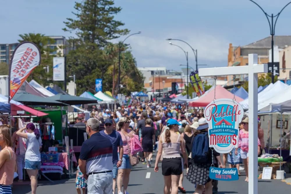 Crowds walking between stalls along the street at Redcliffe Markets