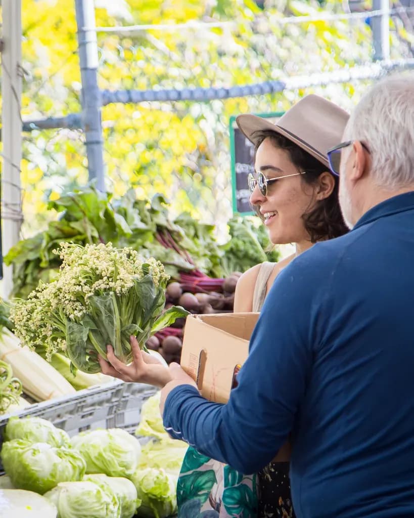 Shopper choosing vegetables at a stall at the Milton Markets