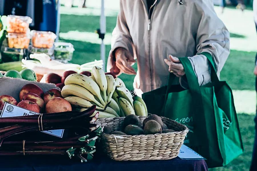 Shopper filling a bag at a fruit stall at The Bunbury Markets