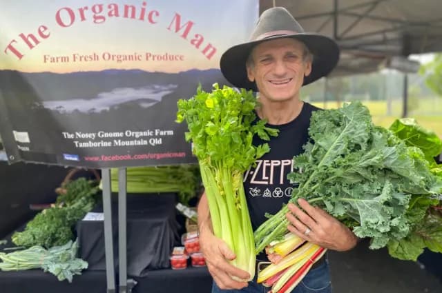Stallholder holding celery and greens at his organic produce stall