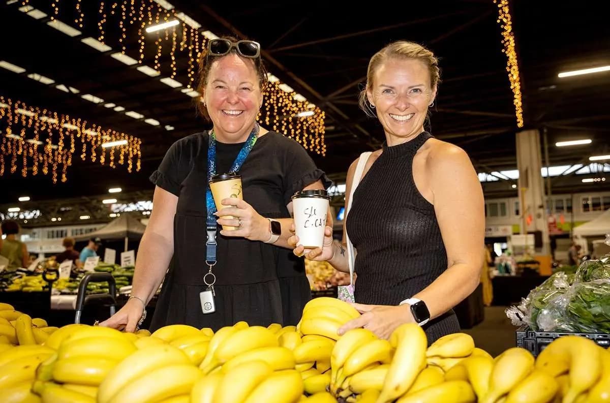 Two stallholders behind a table of bananas at the Saturday Fresh Market in Rocklea